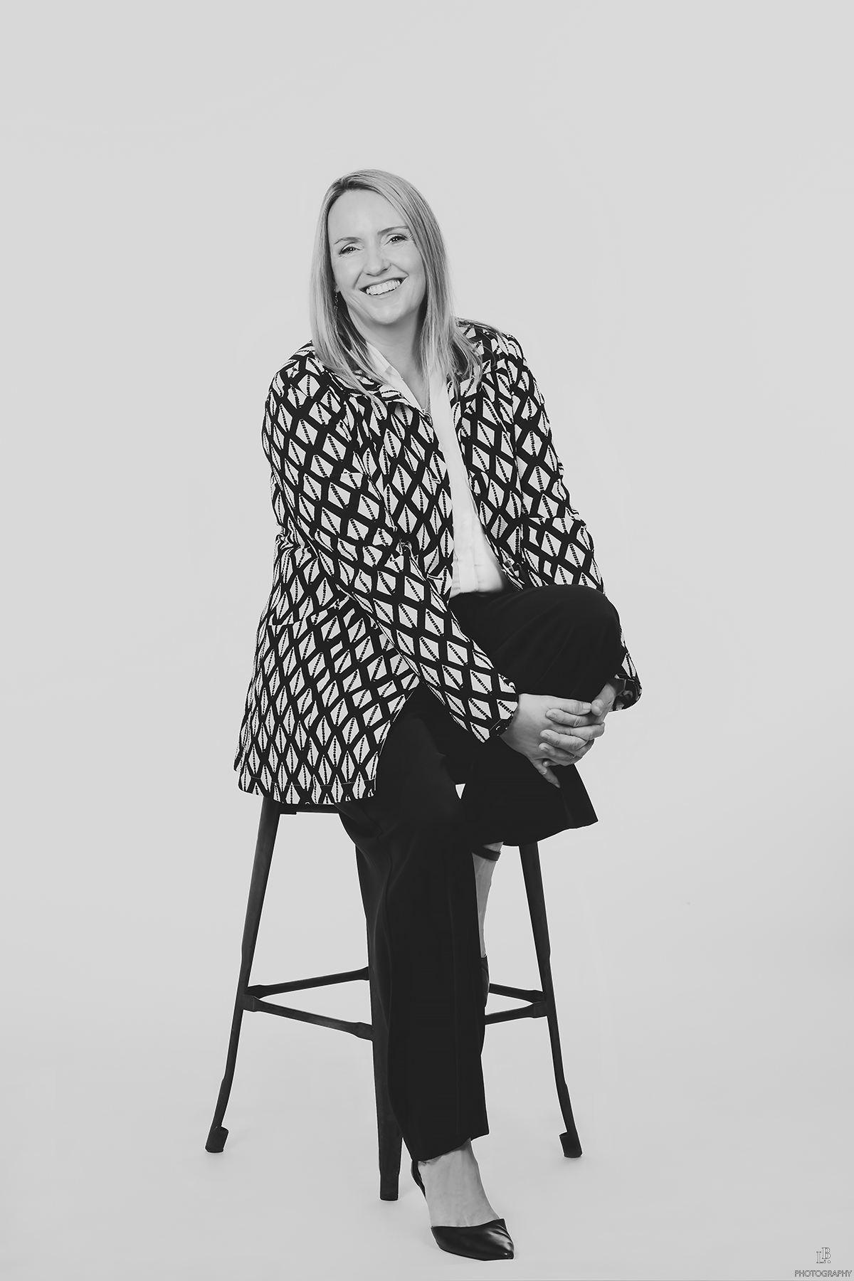 Black-and-white portrait of Angie Hammond seated on a stool